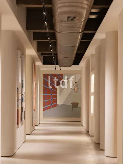 This corridor is defined by its disciplined rhythm, evoking ideas of pause and perspective. The contrast between raw industrial ceiling elements and considered art placements invites both interaction and reflection, turning the passage into a spatial narrative in motion.