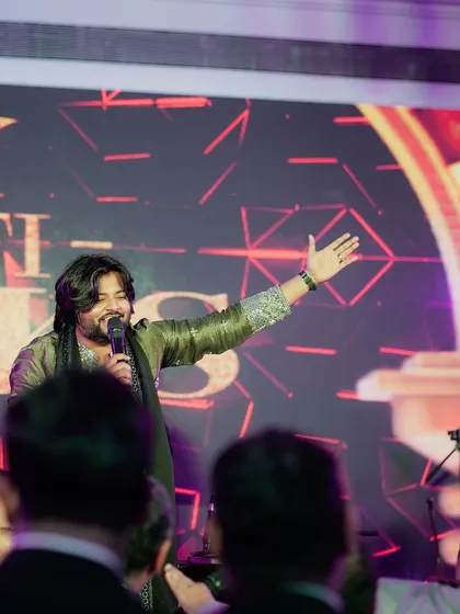 A still photograph capturing our lead singer mid-performance, hand raised in a gesture that connects with the divine essence of the music. This is a typical moment in our soulful sets.
