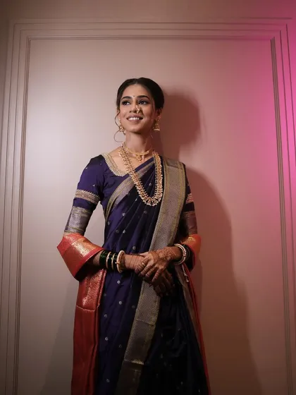 A full-length portrait of the bride in her elegant purple Nauvari saree.