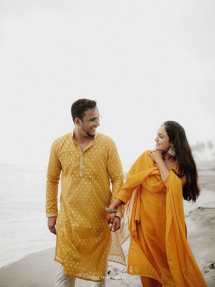 Aiswarya and Vishnu walking hand-in-hand on the beach. The simplicity of this shot allows their happy connection to be the main focus.