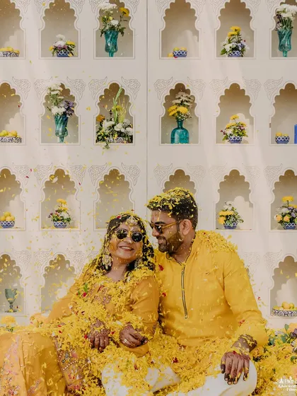 The Haldi ceremony is all about unrestrained joy. We love capturing these playful, candid moments, like Tulsi and Aditya sharing a laugh while being showered with flower petals by their loved ones.