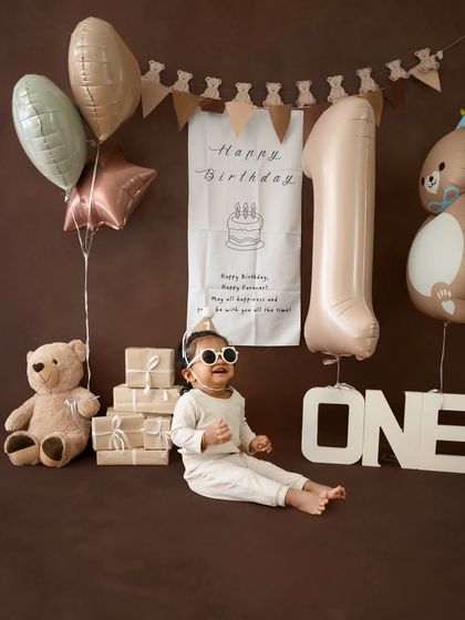 A full-width shot showcasing the entire brown and neutral-toned birthday setup, with the cool little guy posing in the center.