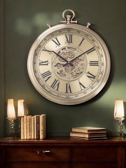 This grand wall clock in a soft champagne finish features classic Roman numerals and an intricate moving gear mechanism. It's a perfect statement piece for a formal living room or entryway.