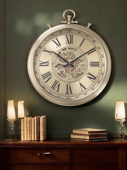 This grand wall clock in a soft champagne finish features classic Roman numerals and an intricate moving gear mechanism. It's a perfect statement piece for a formal living room or entryway.