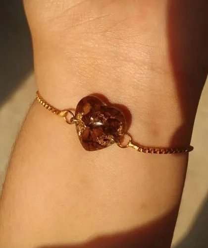 This delicate bracelet features a single heart-shaped charm made from preserved rose petals and gold flakes. It's a subtle yet beautiful way to wear a memory on your wrist every day.