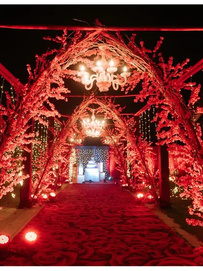 A breathtaking entrance for a night to remember. We designed this stunning red floral tunnel, complete with elegant chandeliers, to create a grand and romantic welcome for a reception at Sula Vineyards.