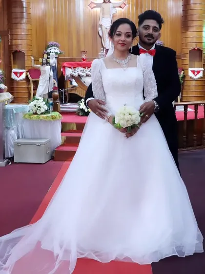 A full portrait of the bride and groom. Her custom gown, with its square neckline and embroidered sleeves, complements the traditional setting beautifully.