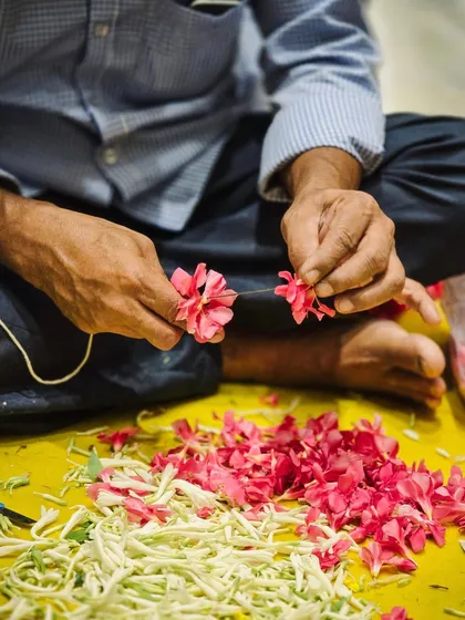 The hands of a craftsman, meticulously creating a floral garland. We honor the skill and dedication of our team, who pour their hearts into every detail.