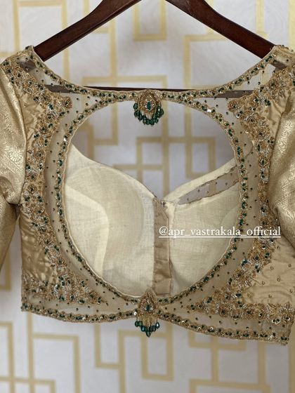 A gold blouse with a sheer back and green stone embroidery.