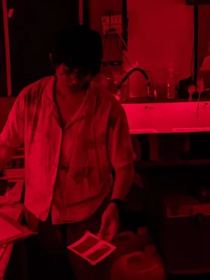 The magical red glow of the darkroom during a printing session for the Our Shared Cultural Heritage project. This is where images come to life through careful, hands-on work.