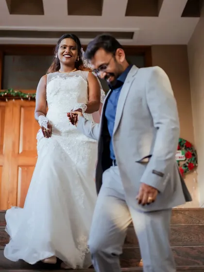 A candid shot of the groom leading his bride down the stairs. The movement and their expressions make this a lively and natural photo.