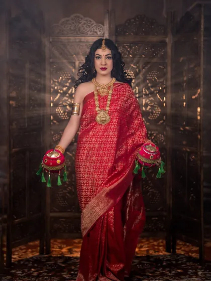 A full-length shot of the goddess look, with a beautiful red silk saree and traditional props.
