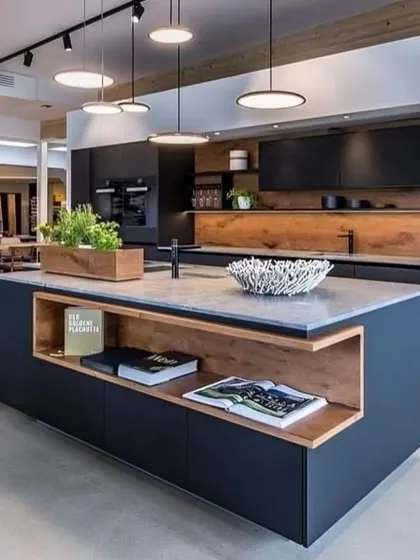 A modern office pantry can be a centerpiece of workplace culture. This design features a large central island with built-in shelving, matte black cabinetry, and warm wood accents, providing a stylish and functional space for employees to connect.