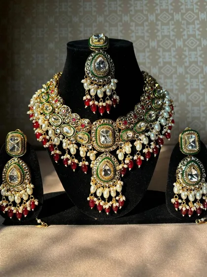 A stunning multi-coloured Kundan necklace set with matching earrings and maang tikka. The combination of red, green, and white stones makes it easy to pair with many bridal outfits.