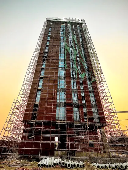 A frontal shot of the same tower under construction. This image provides a clearer view of the exposed brickwork and window placements, showing the raw structure before final completion.