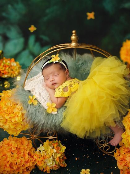 A little ray of sunshine in a bright yellow dress, sleeping in a golden carriage surrounded by vibrant flowers.