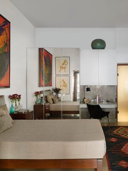 A different angle of the art-filled bedroom, showing how the space is designed to accommodate large canvases and personal collections. The simple, clean lines of the furniture allow the artwork to take center stage.