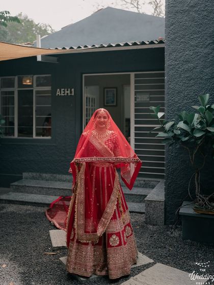 A bride in a vibrant red lehenga stands outside one of our modern cottages. The contrast between the traditional attire and the contemporary architecture is striking.