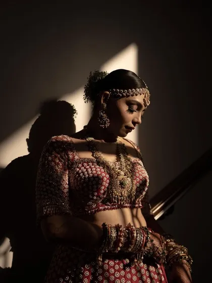 A close-up bridal portrait with dramatic lighting. The play of light and shadow beautifully accentuates the bride's features and the intricate details of her attire.