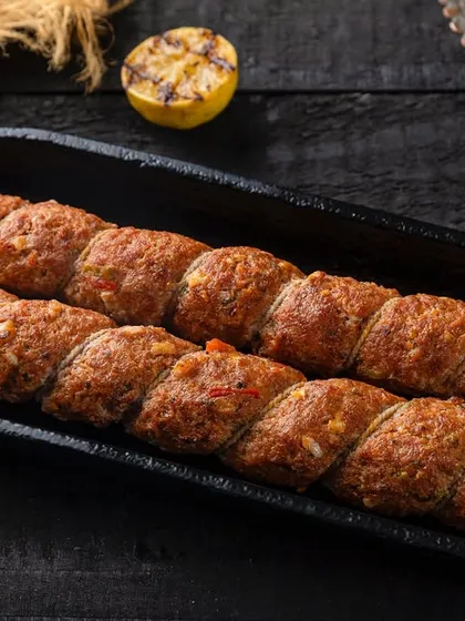 Galouti kebabs presented in a cast-iron dish for Punjab Grill. The dark, textured styling emphasizes the rustic and robust flavors of the dish.