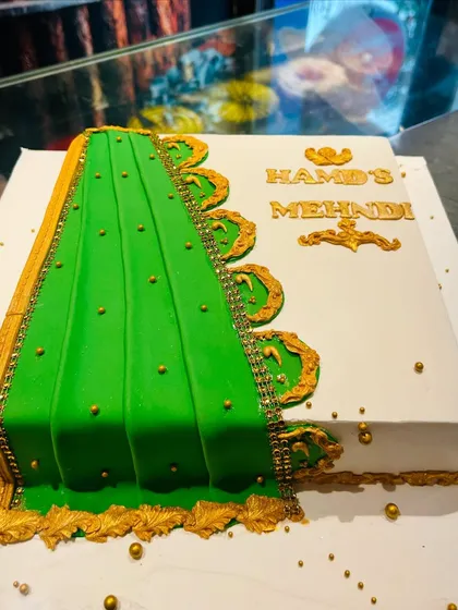 An elegant cake for a Mehndi ceremony, designed to look like a green and gold saree.