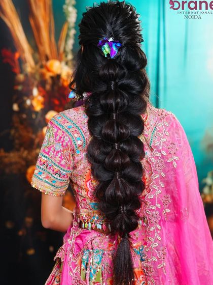 The back view showcases a beautiful, thick bubble braid, an increasingly popular hairstyle for modern brides.