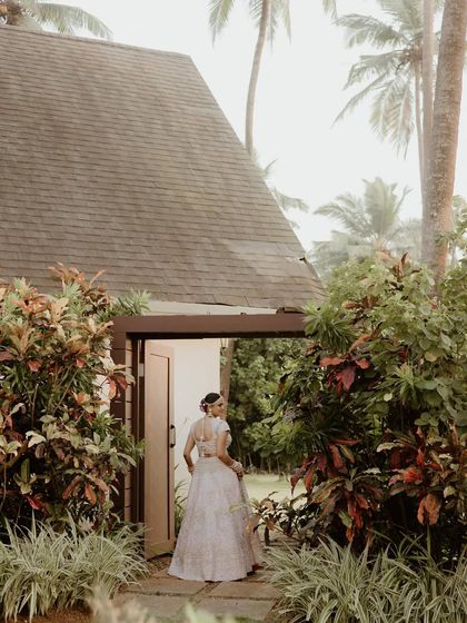 A quiet moment of the bride stepping out of a villa in Goa. The lush greenery and rustic architecture provide a beautiful, natural frame for this candid portrait.