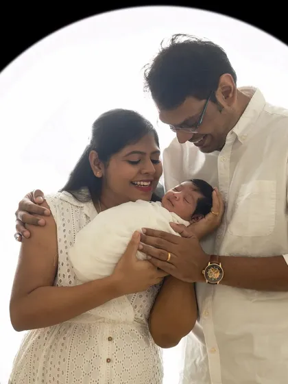 A classic newborn and family portrait. The parents cradle their sleeping baby, creating a memory of peace, love, and the start of their new life together.
