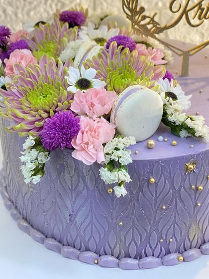 A detailed shot of the fresh flowers and macarons on the lavender cake.