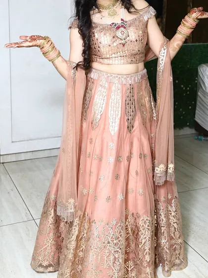 Another look at the peach off-shoulder lehenga, highlighting the delicate tassels on the blouse and the gold embroidery on the skirt.
