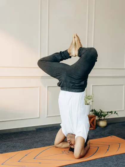This is Sirsasana with legs in Baddha Konasana (Bound Angle). This variation opens the hips while inverted, requiring significant balance and control.