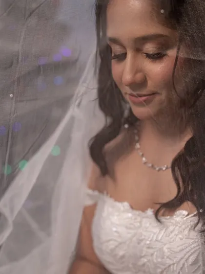 A dreamy, artistic shot of the bride through her veil. The soft focus highlights her gentle features and the romantic quality of her makeup.