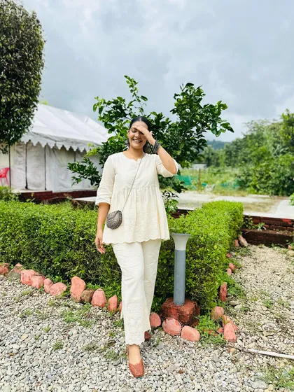 This small, round woven sling bag is a subtle yet stylish accessory. Its dark, earthy tone provides a lovely contrast against this all-white outfit, perfect for a vacation or a summer day.