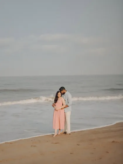 A quiet embrace at the edge of the ocean. This wide shot emphasizes the peaceful, romantic setting of their beach pre-wedding session.