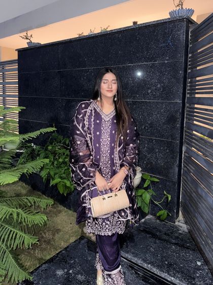 Posing with a golden clutch that perfectly matches the festive vibe of the purple suit.