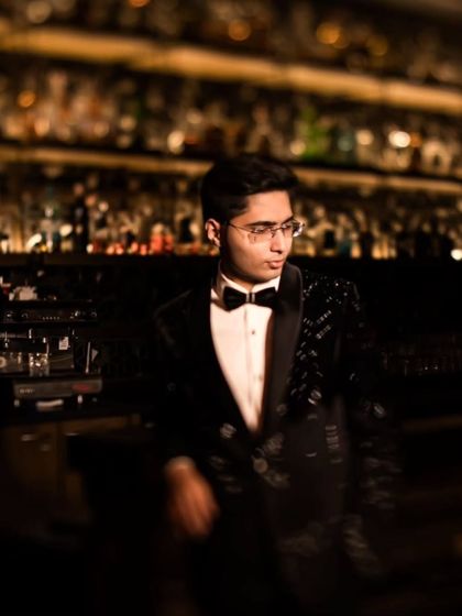 The groom looking dapper and relaxed against the backdrop of a bar, a stylish solo shot from the cocktail night.
