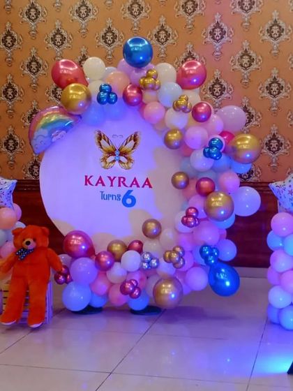 A butterfly-themed 6th birthday with a custom-lit backdrop and a colorful balloon arch.