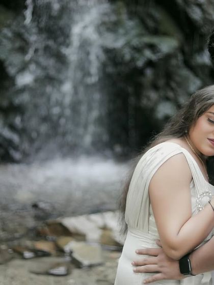 A tender embrace by a waterfall. The focus is on their emotional connection, with the cascading water providing a beautiful, textured background.