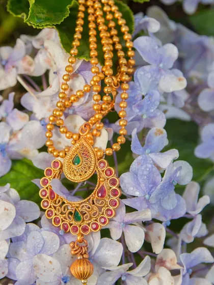 An artistic shot of a traditional piece of South Indian bridal hair jewelry, set against a bed of flowers. We appreciate and know how to capture the beauty of accessories from different cultures.