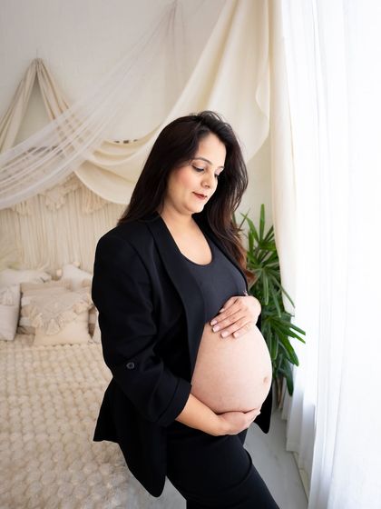 A modern and powerful "boss lady" portrait. The mom-to-be wears a black blazer over her bare bump, exuding confidence and style in this unique lifestyle shot.
