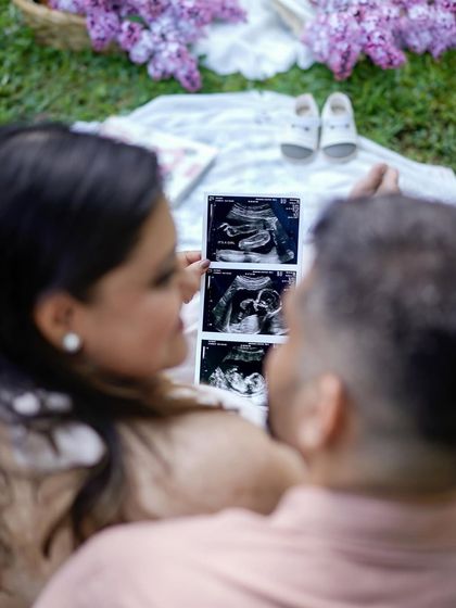 A beautiful detail shot from an outdoor picnic, with the couple looking at their sonogram pictures together.