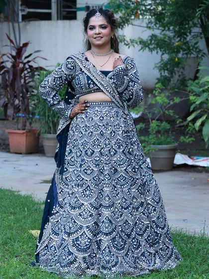 A full-length view of our popular navy blue and silver lehenga. The intricate, scalloped embroidery pattern covers the entire skirt, creating a heavy, luxurious look for any grand wedding function.
