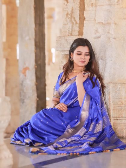 Portraits of a model in a vibrant blue saree, shot within the historic and atmospheric corridors of a temple. The stone pillars and natural light create a dramatic and timeless setting.