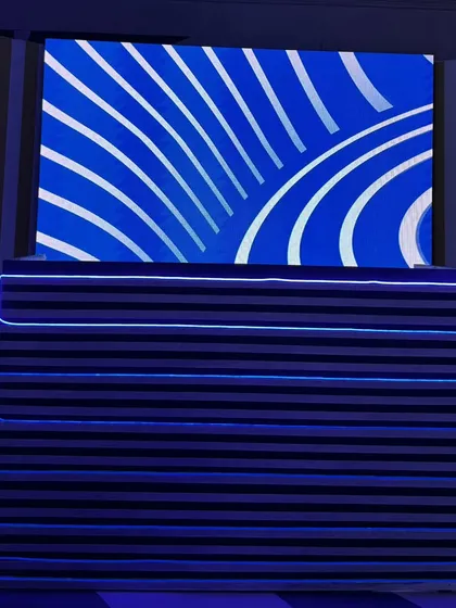 The custom-designed DJ console for the Uttarayan party. The console is wrapped in fabric with neon light accents, and the LED screen behind it displays graphics that match the event's modern, artistic theme.