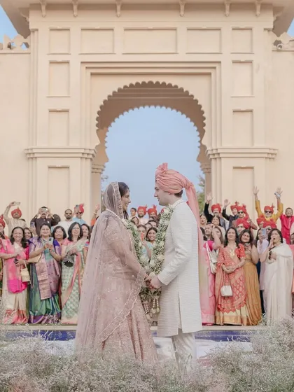 Pearl and James share a look after their varmala at the Oberoi Udaivilas in Udaipur. The stunning architecture and the cheering crowd create a perfect destination wedding moment.