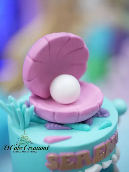 A close-up of the edible oyster and pearl topper, a signature detail of the mermaid cake.