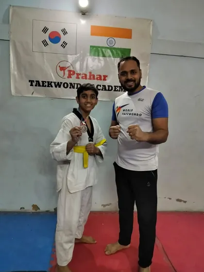 A yellow belt student proudly shows off his medal from the district championship.