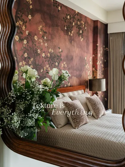 This bedroom wall is enveloped in a moody, textured wallpaper with scattered blossoms. The design, reflected in the mirror, creates a romantic and immersive atmosphere.