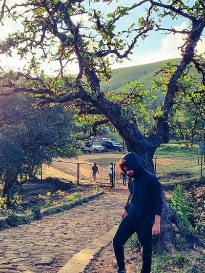 A traveler on a path at Mandalpatti, Coorg, with the sun setting over the hills. The lighting and scenery here are a photographer's dream.