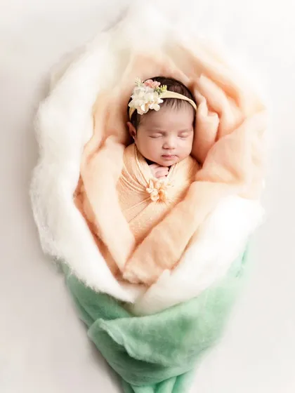 This newborn is wrapped to look like a little flower bud. We use creative wrapping techniques to create unique and artistic portraits.